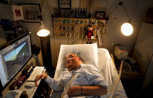 Paulo Henrique Machado deitado na cama do hospital, ao lado do computador de onde criou toda a sua animação