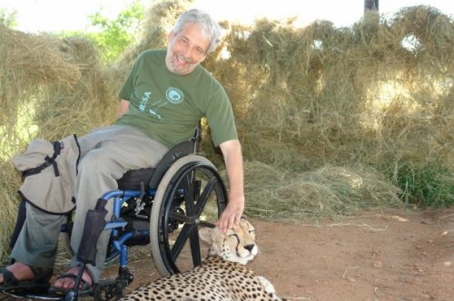Scott Rains faz carinho em um Guepardo num safari na África do Sul
