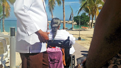A traveler in a wheelchair is escorted by a tour guide at the Riu Palace Jamaica in Montego Bay
